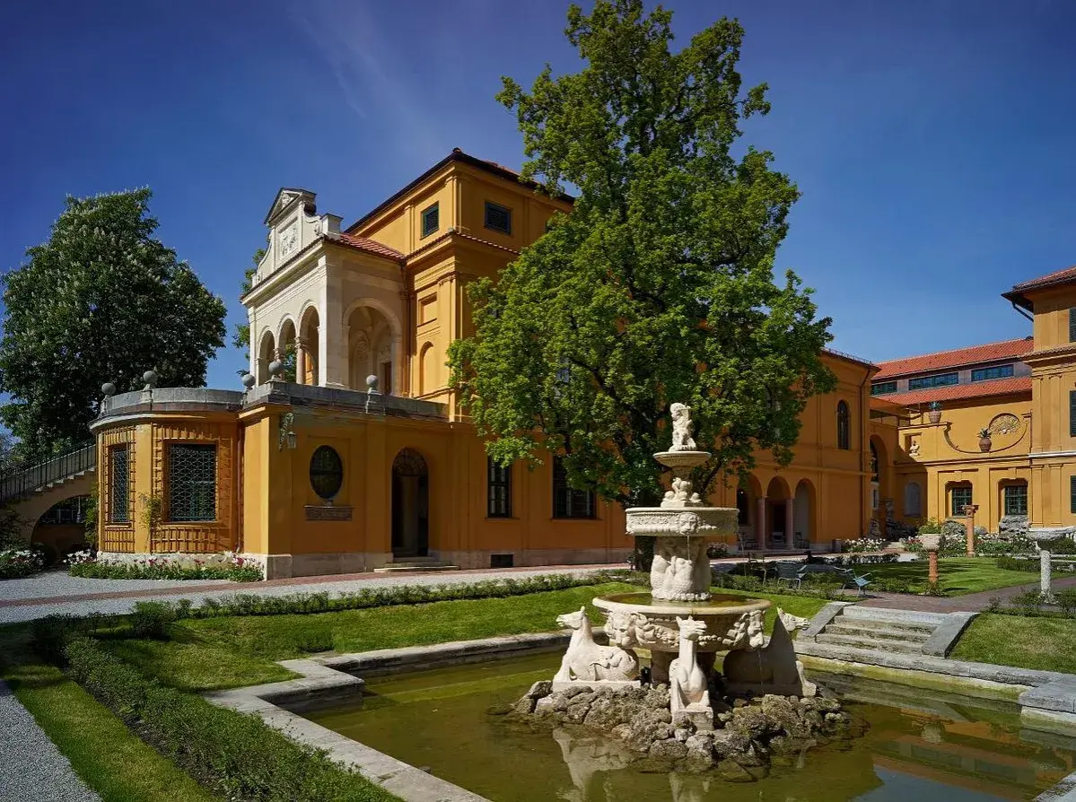 Der kunstbau lenbachhaus mit seinem gelben Anbau und dem Brunnen im Garten.