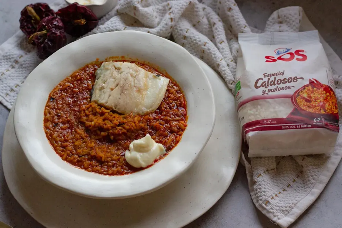 Un plato de caldero murciano con pescado y un toque de alioli, acompañado de arroz especial caldoso y pimientos secos.