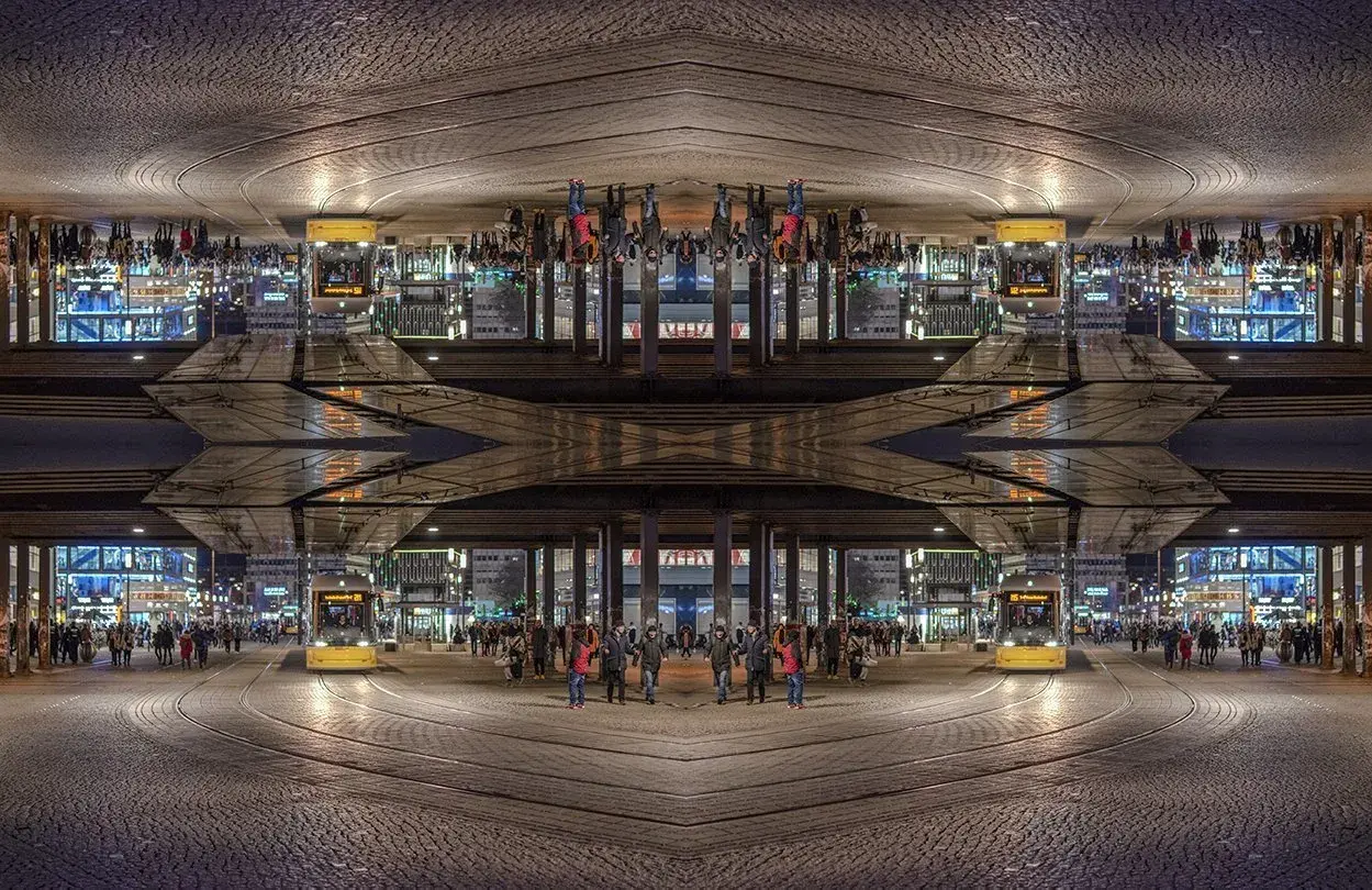 Nocne miasto z żółtym tramwajem i ludźmi. Kompozycja symetryczna tworzy surrealistyczny obraz.