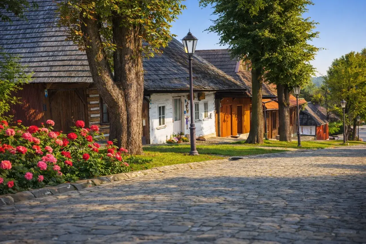 Urokliwa wieś, idealne miejsce, gdzie na wakacje w Polsce. Brukowana droga, kwitnące róże i tradycyjne chaty tworzą sielski klimat.