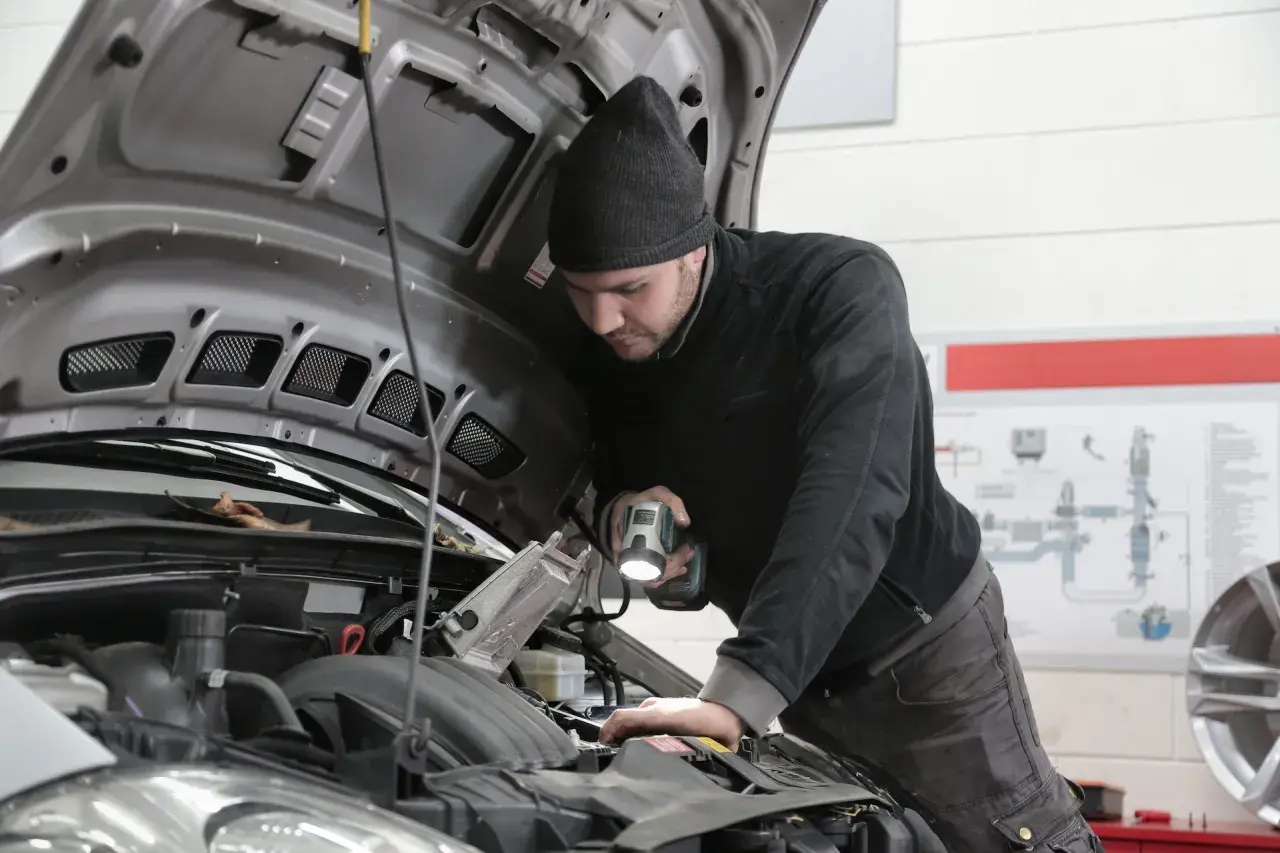 Mechanik sprawdza silnik, szukając przyczyny awarii. Zastanawiasz się, ile kosztuje naprawa silnika w samochodzie?