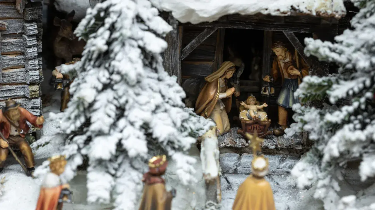 Winterliche Krippenszene mit Maria, Josef und dem Jesuskind. Hirten und Könige nähern sich der Stallung. Ein Sinnbild für Weihnachten und das Christentum.