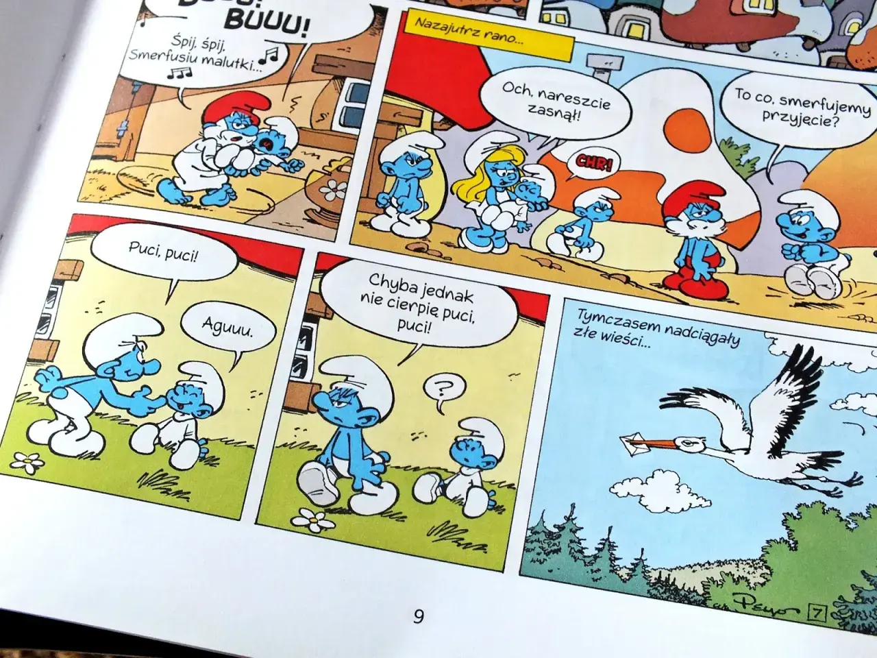 Fragment komiksu ze Smerfami: Papa Smerf usypia Smerfusia, inne Smerfy rozmawiają, a bocian niesie list.