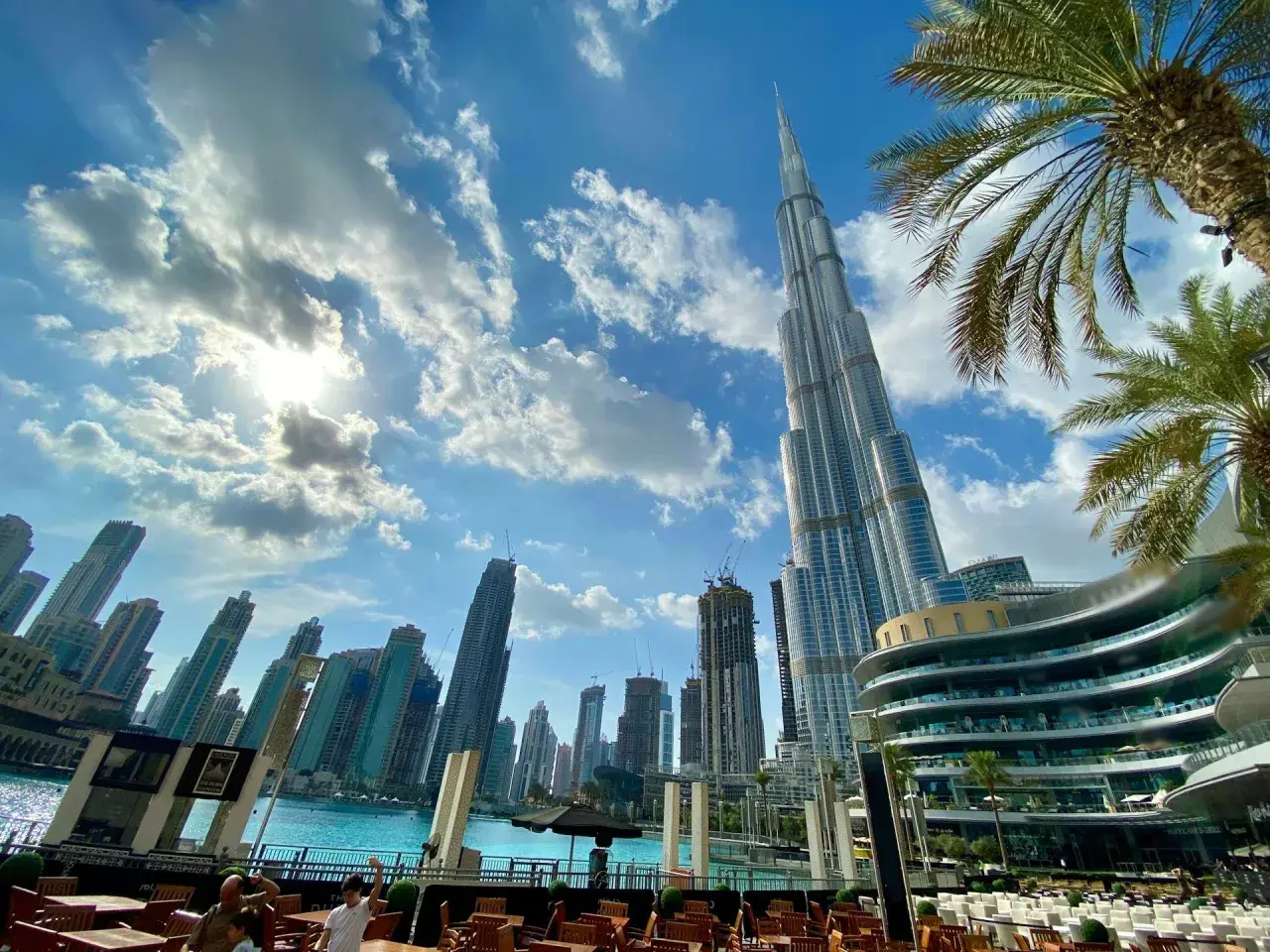 Burj Khalifa i inne drapacze chmur w Dubaju. Słońce przebija się przez chmury. Warto zabrać do Dubaju okulary przeciwsłoneczne i lekki ubiór.