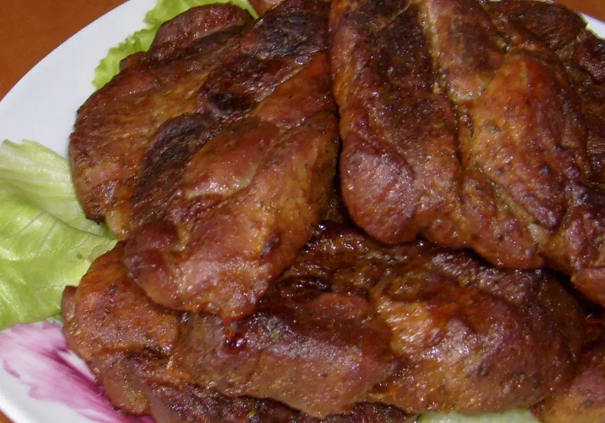 Soczysta karkówka pieczona na talerzu z sałatą.