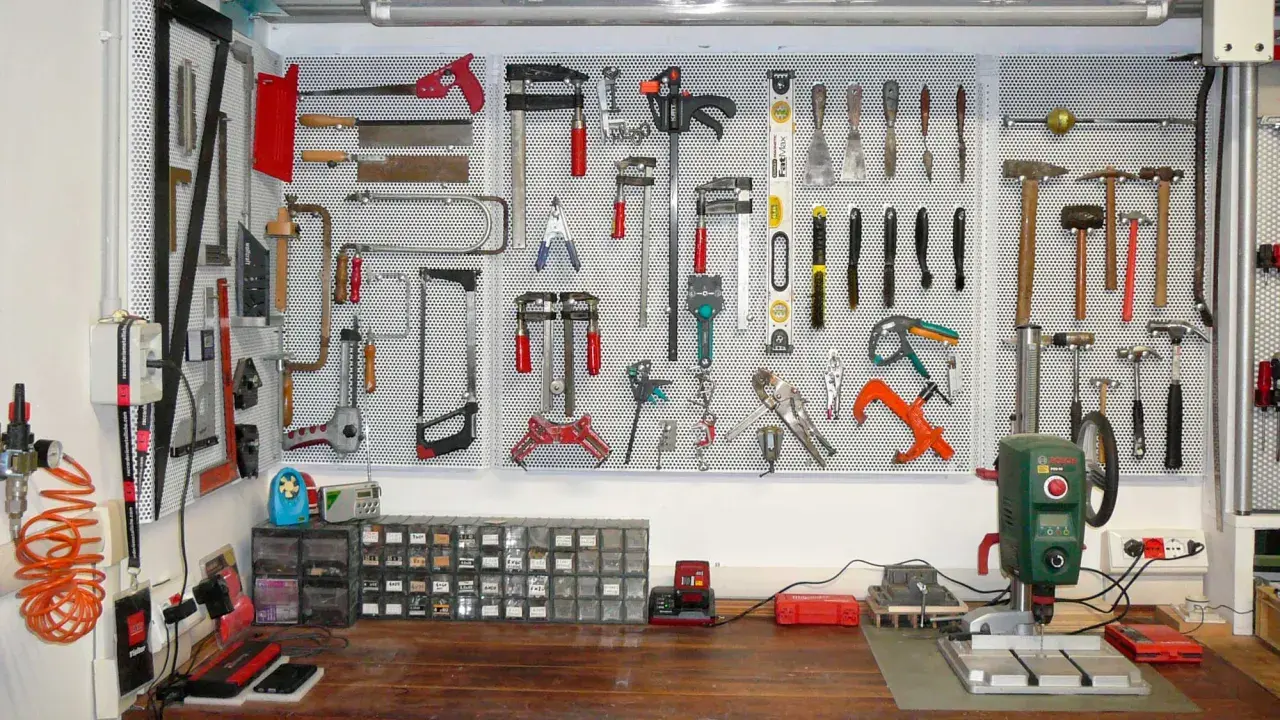 Parete porta attrezzi con pallet, organizzata con martelli, seghe, pinze e altri strumenti.