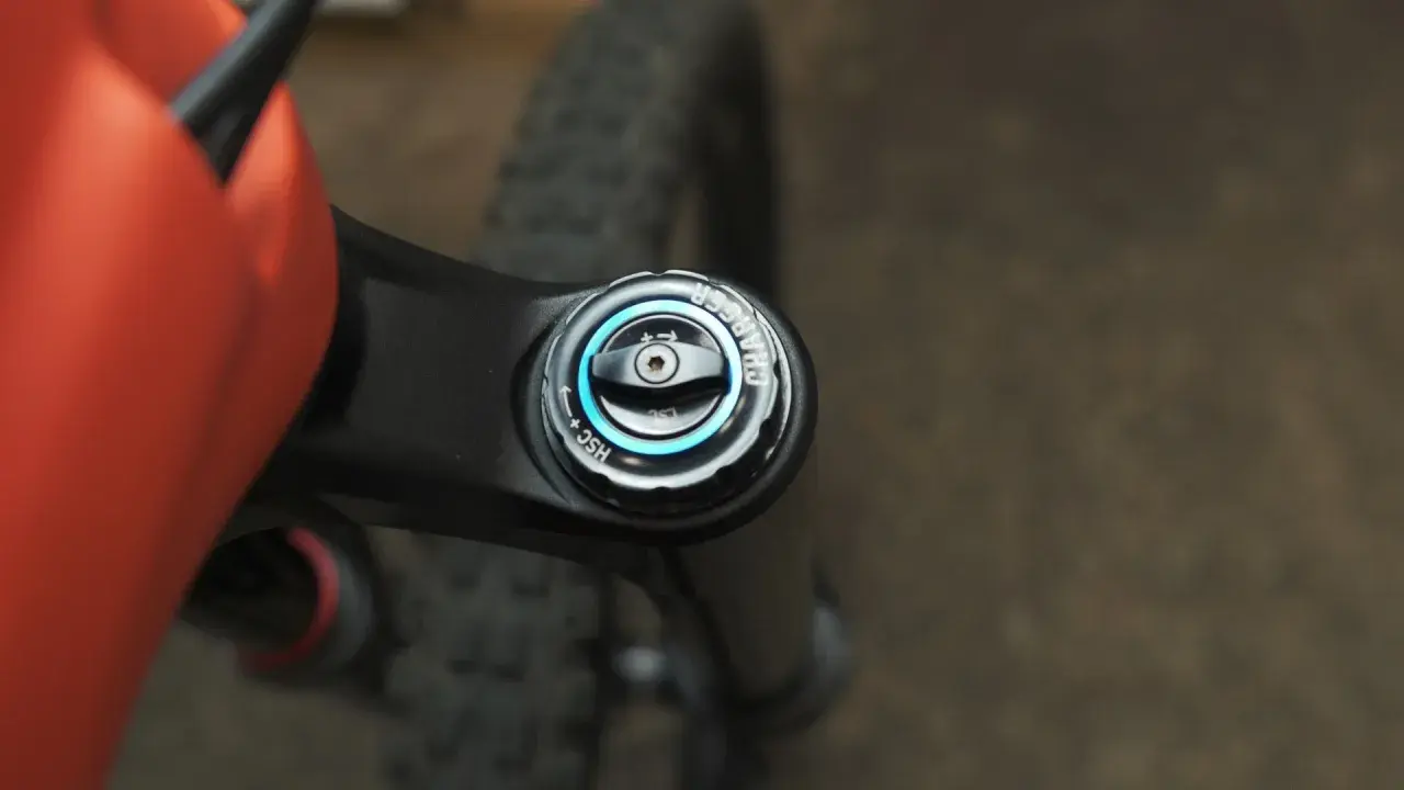 Close-up of an orange MTB frame and black suspension fork with a "Charger" damper adjustment knob, part of the mtb suspension setup.