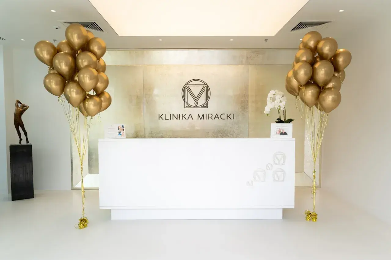 Recepcja kliniki z bukietami złotych balonów i logo.