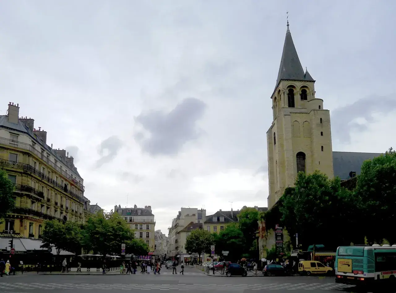 Wieża kościoła Saint-Germain-des-Prés na tle paryskiej ulicy z budynkami i przechodniami.