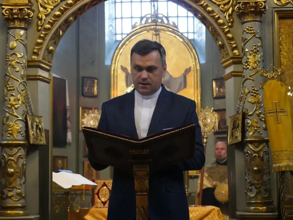 Duchowny w kościele polskokatolickim czyta z księgi. Różnice między kościołem polskokatolickim a rzymskokatolickim są widoczne w wystroju.