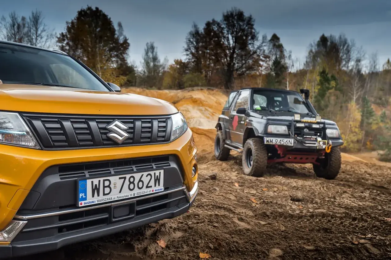 Żółty Suzuki Vitara 2025 i czarny, terenowy model na piaszczystym podjeździe.