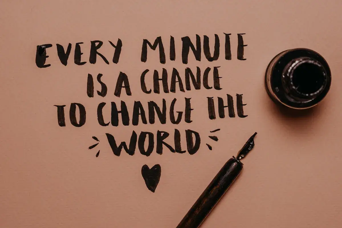 Every minute is a chance to change the world" - frasi motivazionali brevi in inglese scritte a mano con pennino e calamaio.