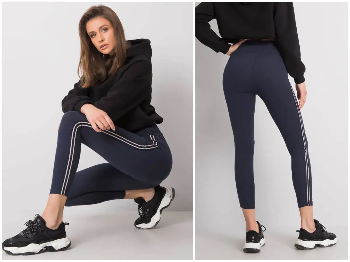Modelka prezentuje granatowe legginsy z lampasami. Idealne do sportowych stylizacji, świetnie wyglądają z bluzą i sneakersami. Co założyć do legginsów? Taki zestaw to strzał w dziesiątkę!