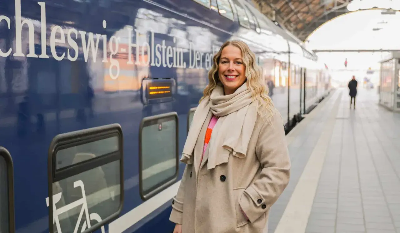 Frau am Bahnsteig in Schleswig-Holstein, bereit für neue Abenteuer. Hier sind einige Flensburg Tipps für deine Reise!