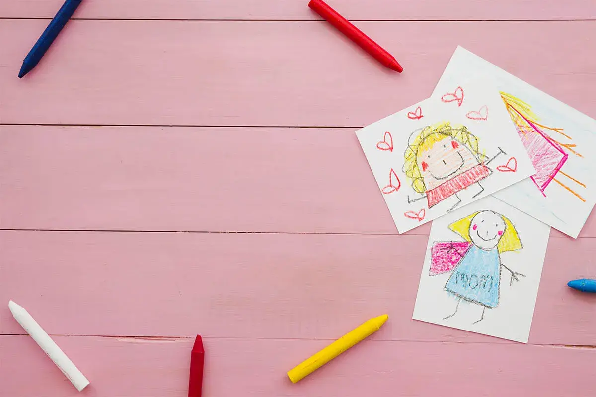 Dziecięce rysunki i kredki na różowym tle. Może to być ilustracja do sprawy o pozew o alimenty na dwoje dzieci.