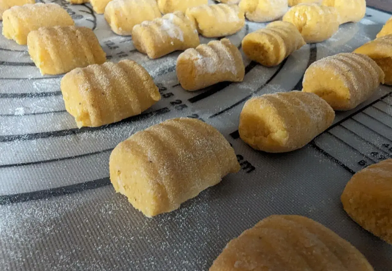 Gnocchi de patate douce faits maison, prêts à être cuits, saupoudrés de farine sur une planche.