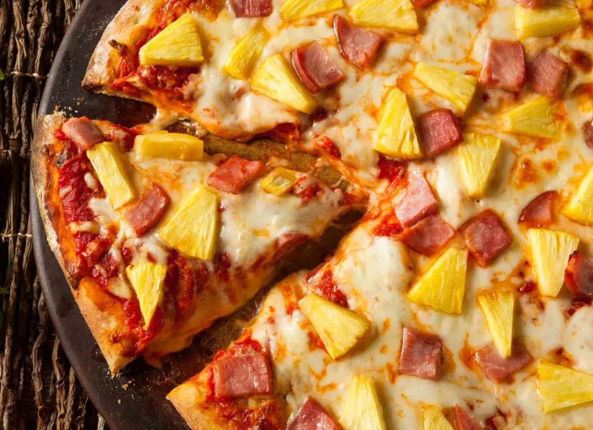 Pyszna pizza z ananasem i szynką, z ciągnącym się serem i chrupiącym ciastem. Idealna na szybki obiad.