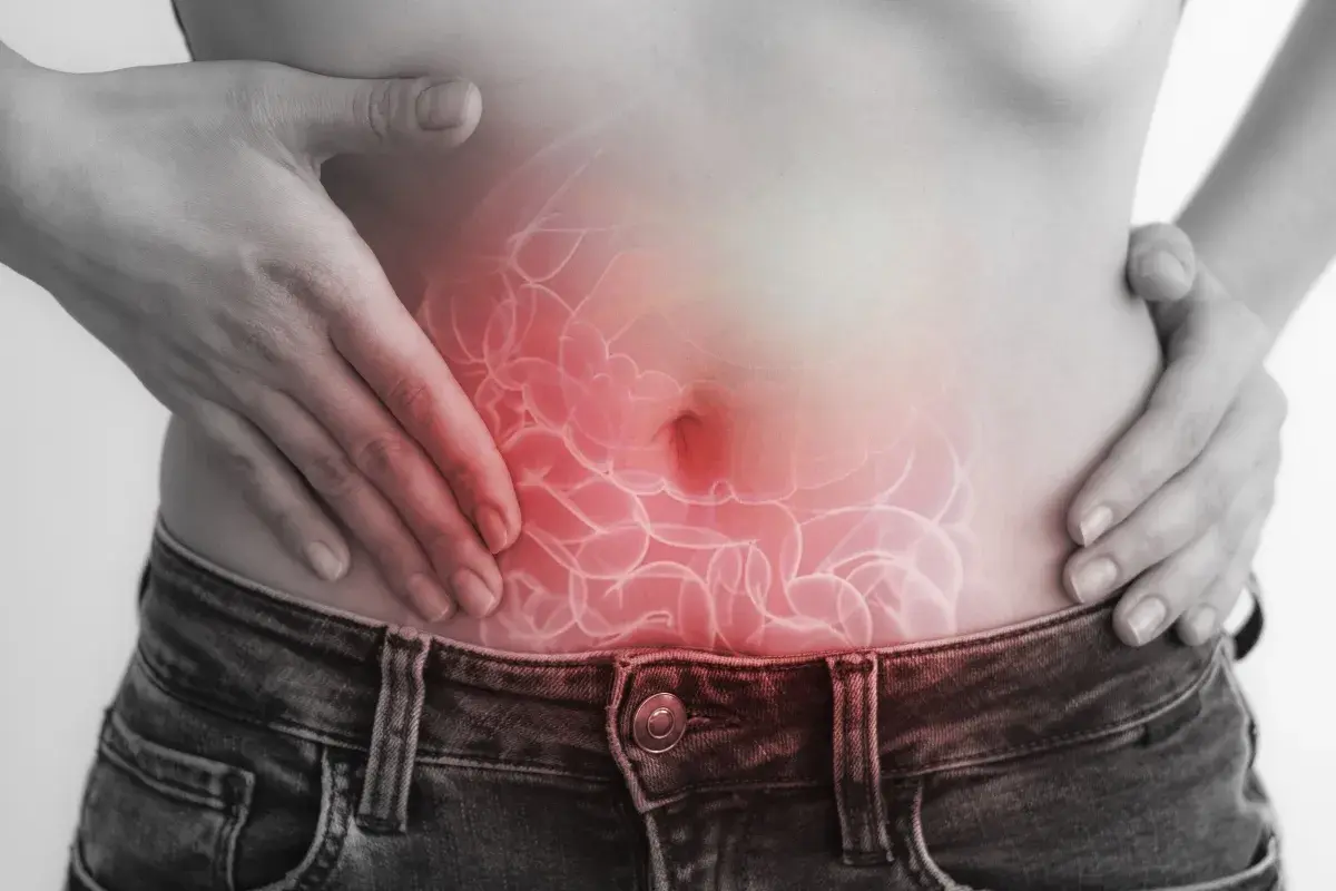 Dolore addominale, forse legato a escherichia coli in gravidanza. Mani sulla pancia con un'illustrazione degli intestini infiammati.
