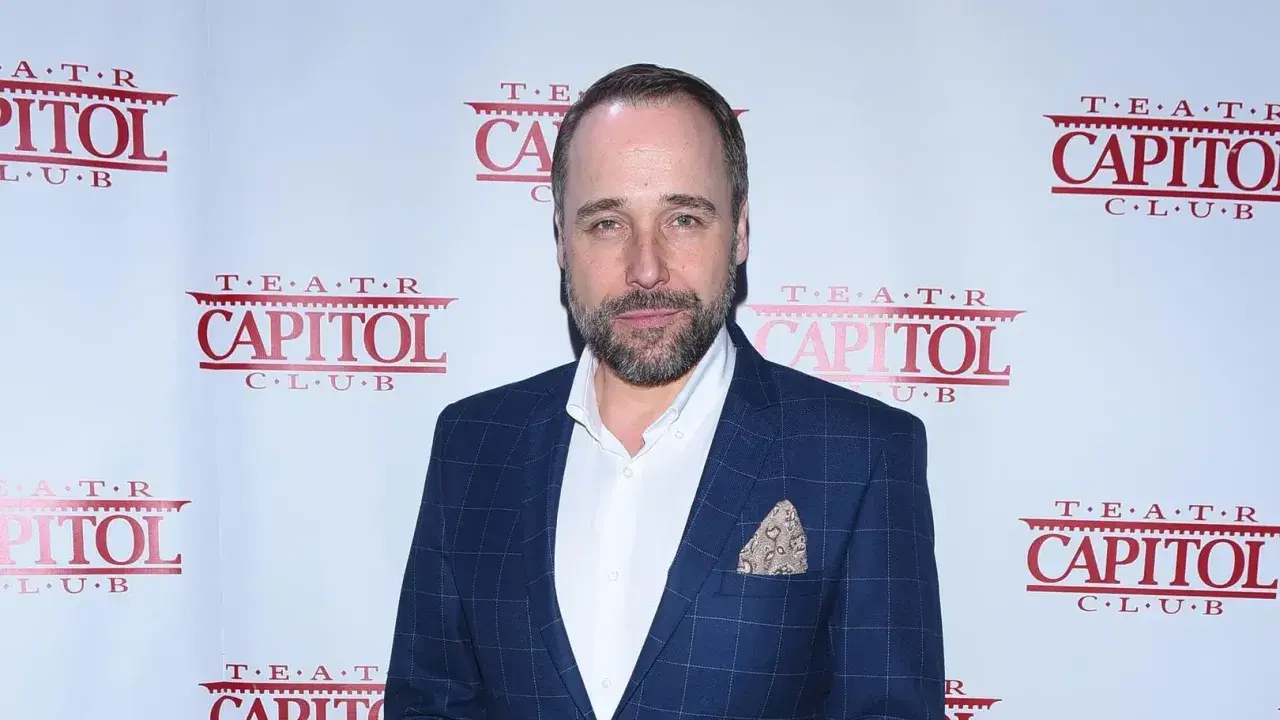 Łukasz Nowicki, znany z wielu filmów, pozuje na tle ścianki z logo Teatru Capitol.