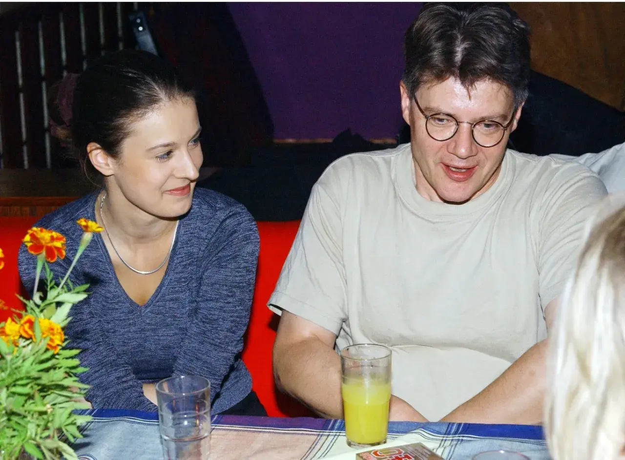 Mirosław Konarowski w prywatnym życiu, uśmiechnięty, siedzi przy stole z kobietą.