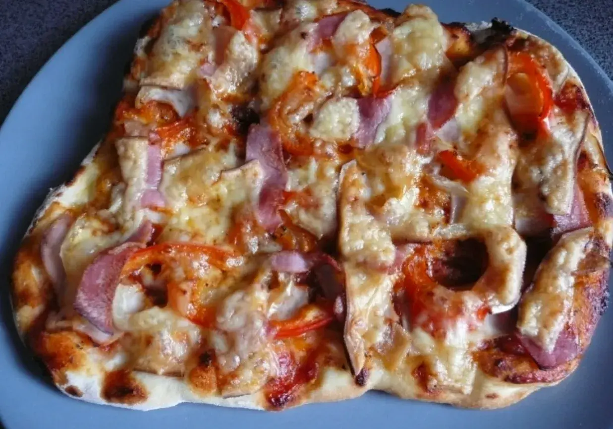 Pyszna pizza z szynką, papryką i cebulą, zapieczona pod ciągnącym się serem. Idealna na szybki obiad.