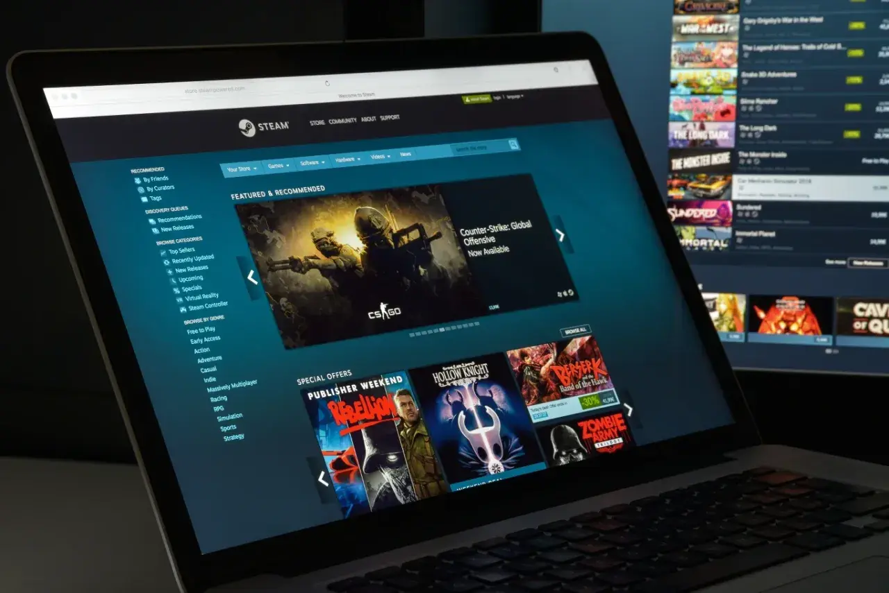 Ekran laptopa z witryną Steam, pokazujący jak działa udostępnianie gier. Widoczne gry i oferty specjalne.