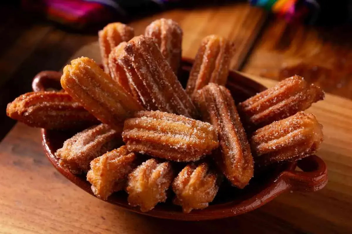 Un piatto colmo di churros dorati, cosparsi di zucchero. Una deliziosa churros ricetta da gustare.
