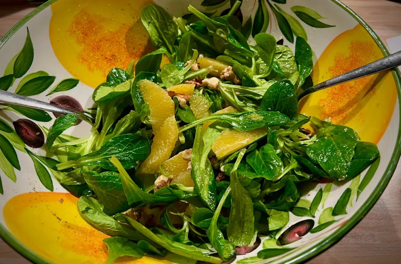Frischer Feldsalat mit saftigen Orangenspalten und Nüssen, serviert in einer bunten Schüssel mit Zitrusfrüchten-Motiv.