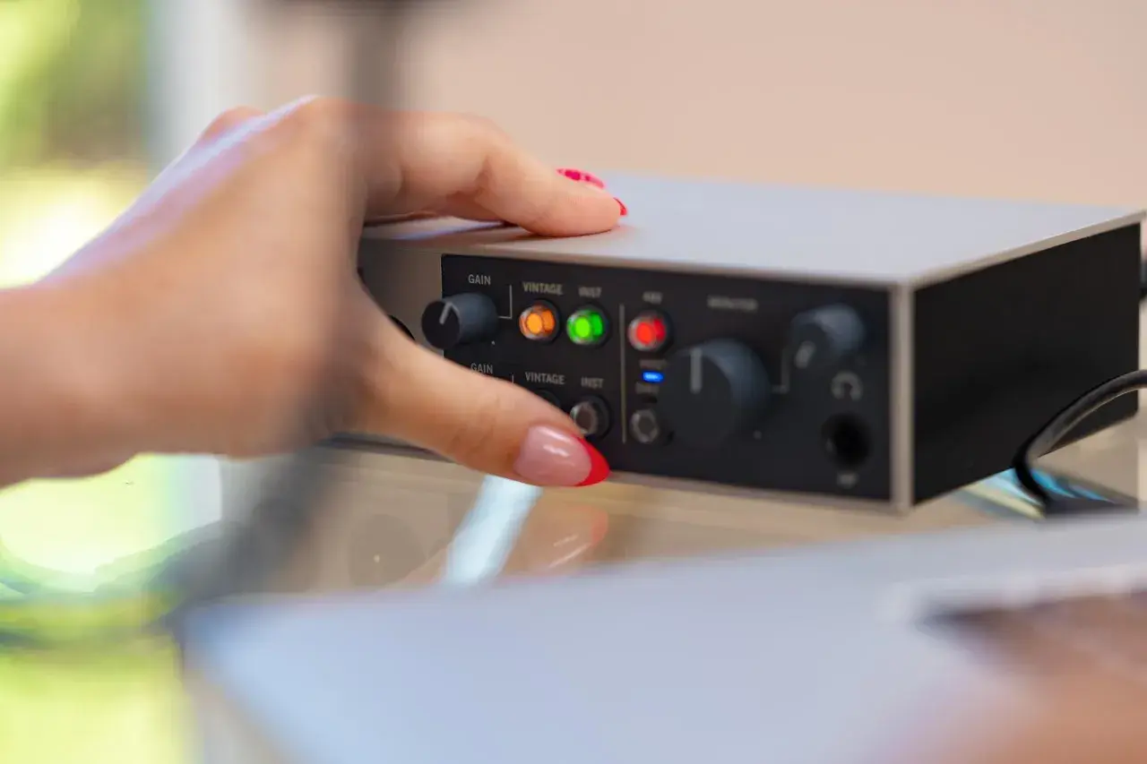 Dłoń z paznokciami ustawia pokrętło na interfejsie audio. Dowiedz się, jak podłączyć mio smartbox iii.