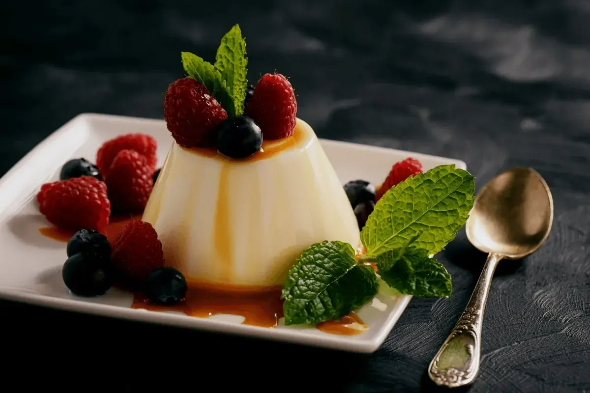 Panna cotta z malinami i borówkami, polana syropem. Idealny deser, gdy szukasz prostego panna cotta przepis.