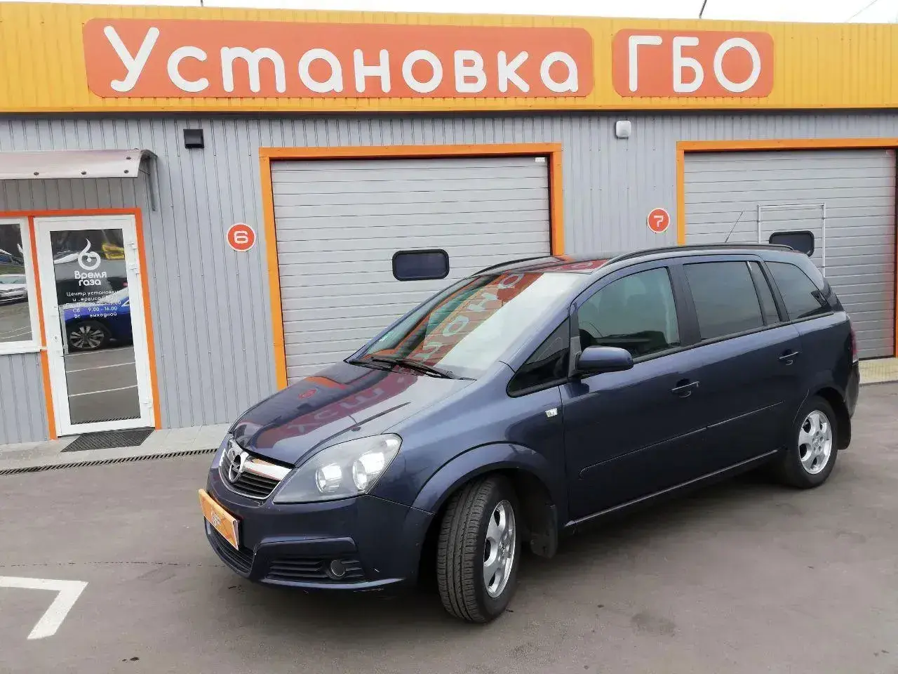 Opel Zafira 1.6 benzyna opinie: rodzinny van przed budynkiem z napisem "Установка ГБО".