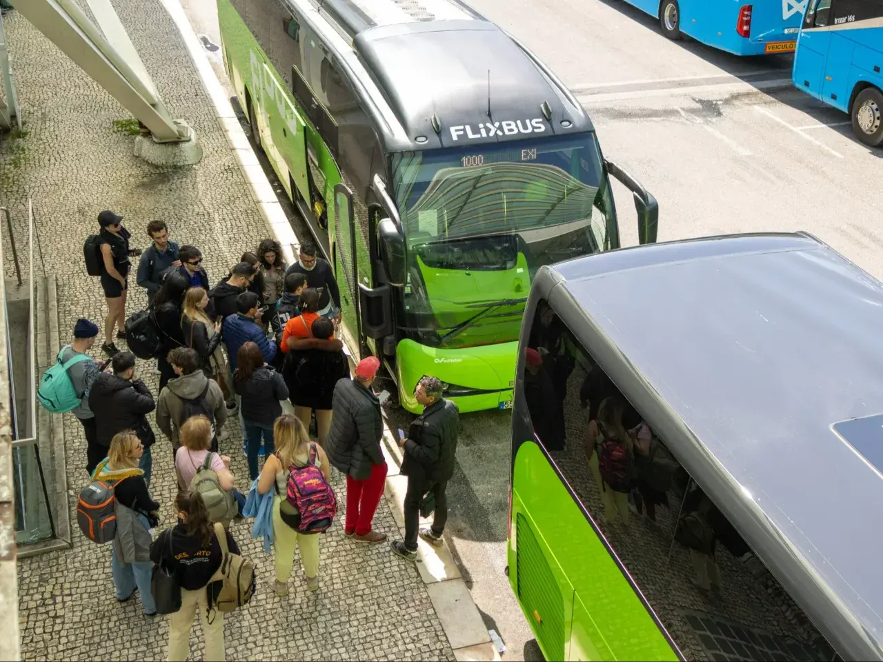 Grupa ludzi czeka na zielonego Flixbusa, szukając okazji na podróż.