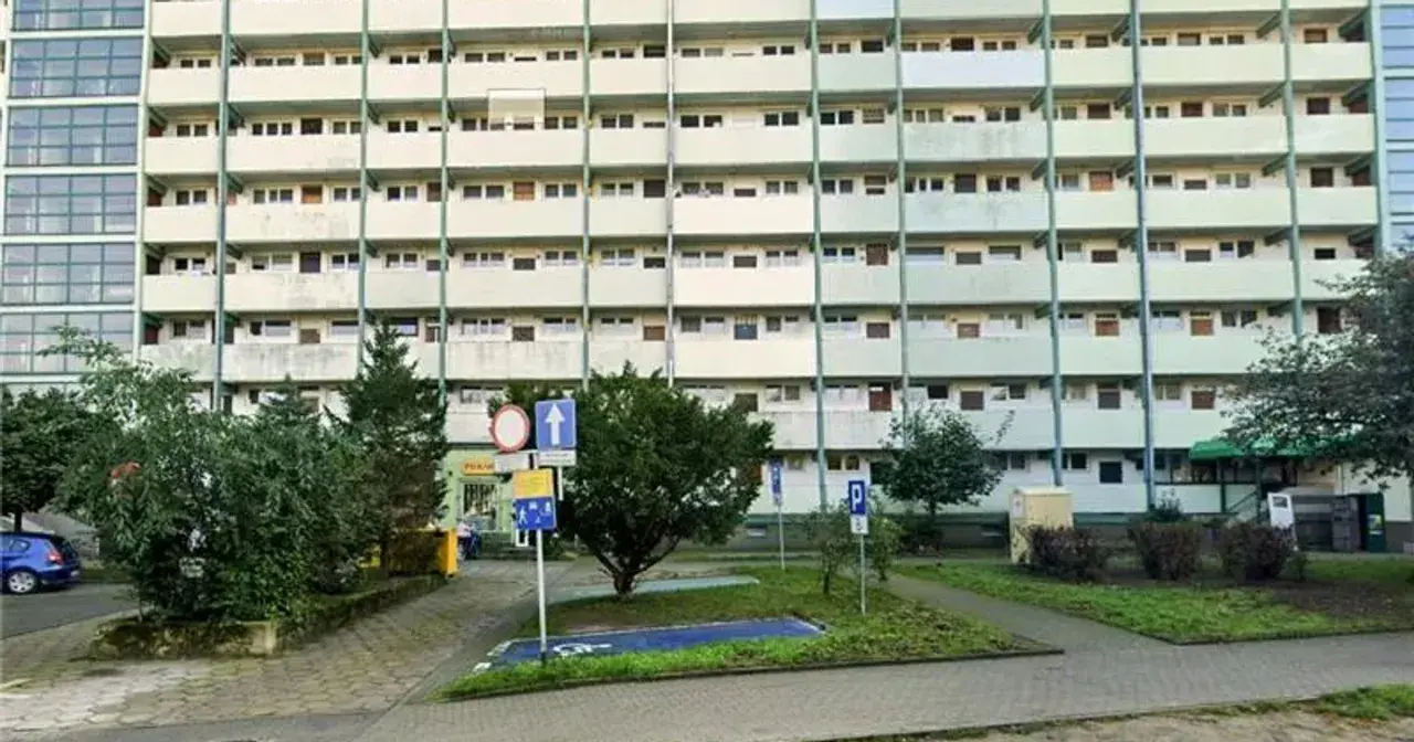 Wyznaczono miejsce dla niepełnosprawnych bez koperty, obok zieleni i bloków mieszkalnych.