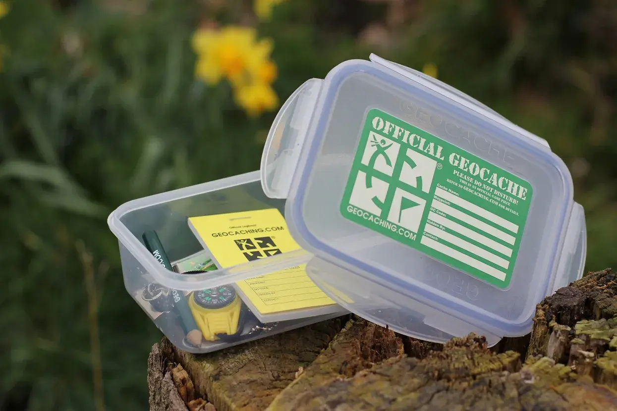 Pudełko z napisem "Official Geocache" i kompasem. To jest właśnie geocaching – zabawa w poszukiwanie skarbów.