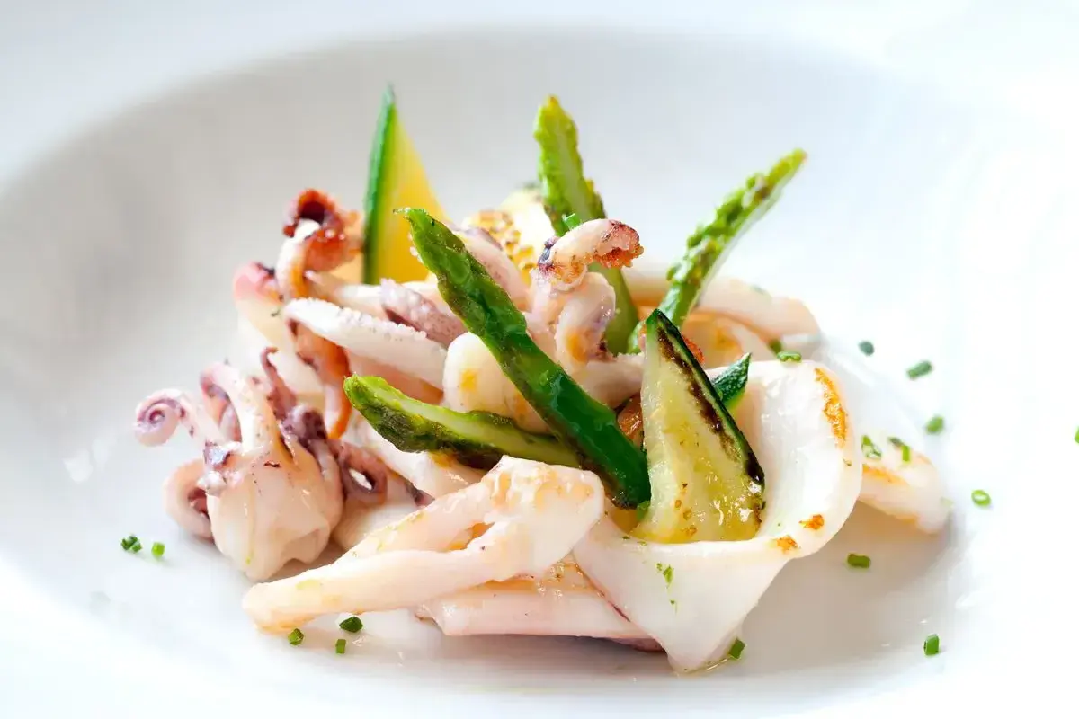 Deliziosa insalata di seppie gourmet con asparagi croccanti e zucchine grigliate, guarnita con erba cipollina.