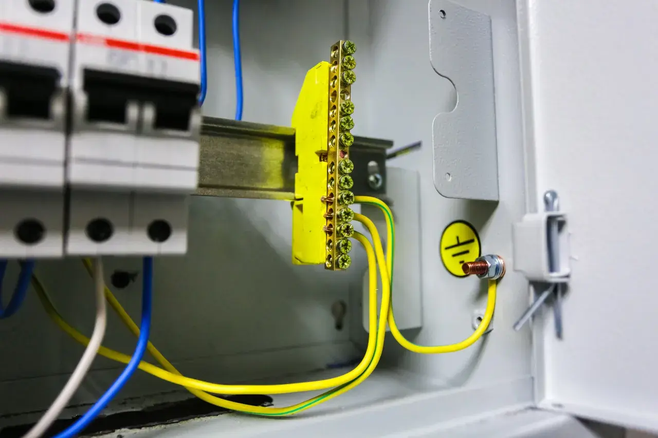 Instalacja elektryczna z wyłącznikami i listwą zaciskową. Pokazuje, jak zrobić uziemienie szpilkowe, łącząc przewody z listwą i obudową.