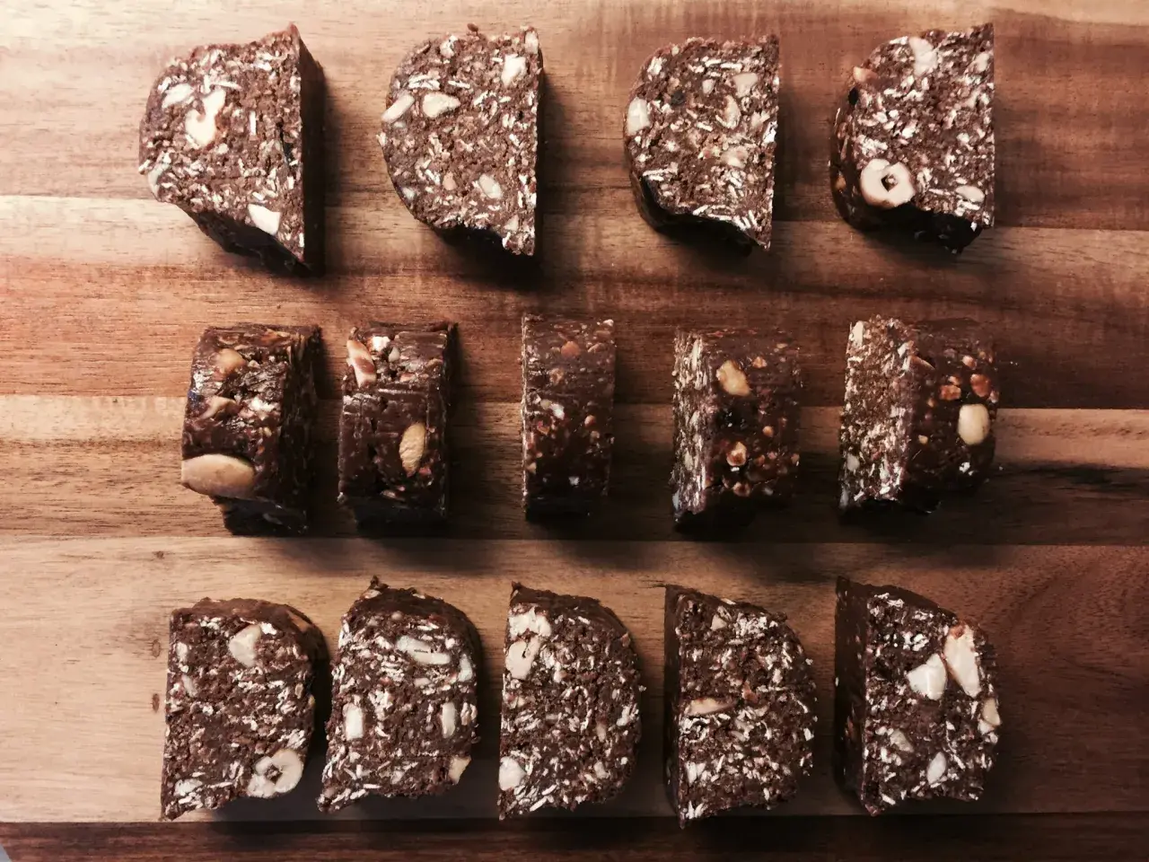 Chokladiga egna bars med nötter och kokos, upplagda på en träskärbräda.