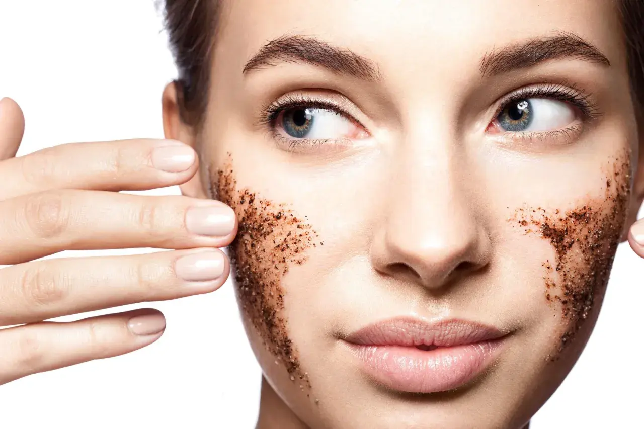 Une femme applique un gommage visage à base de grains de café. Elle montre comment faire un gommage visage pour une peau douce.