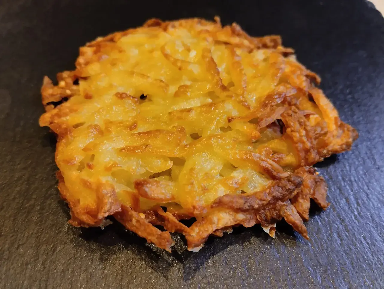 Un croccante rosti di patate dorato, preparato con patate grattugiate e cotto fino a ottenere una deliziosa crosticina.