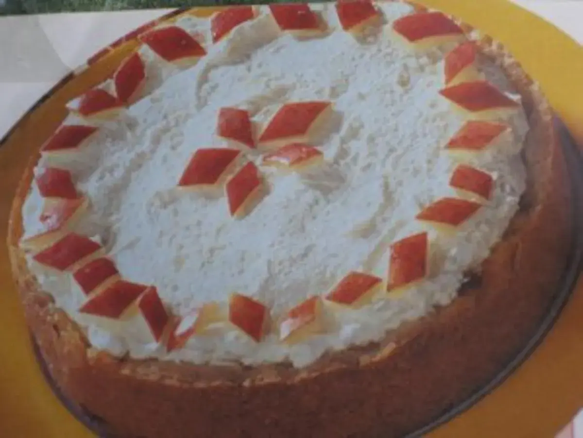 Eine köstliche Apfel Sekt Torte mit Sahnehaube und roten Apfelstücken verziert.