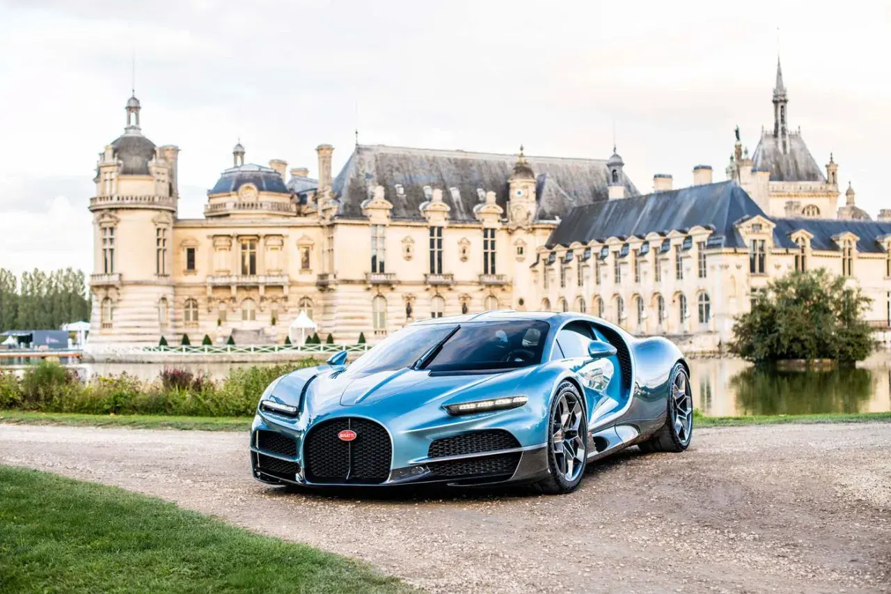 Błękitne Bugatti Chiron przed zamkiem. Zastanawiasz się, ile kosztuje Bugatti? To marzenie wielu, ale cena jest astronomiczna.