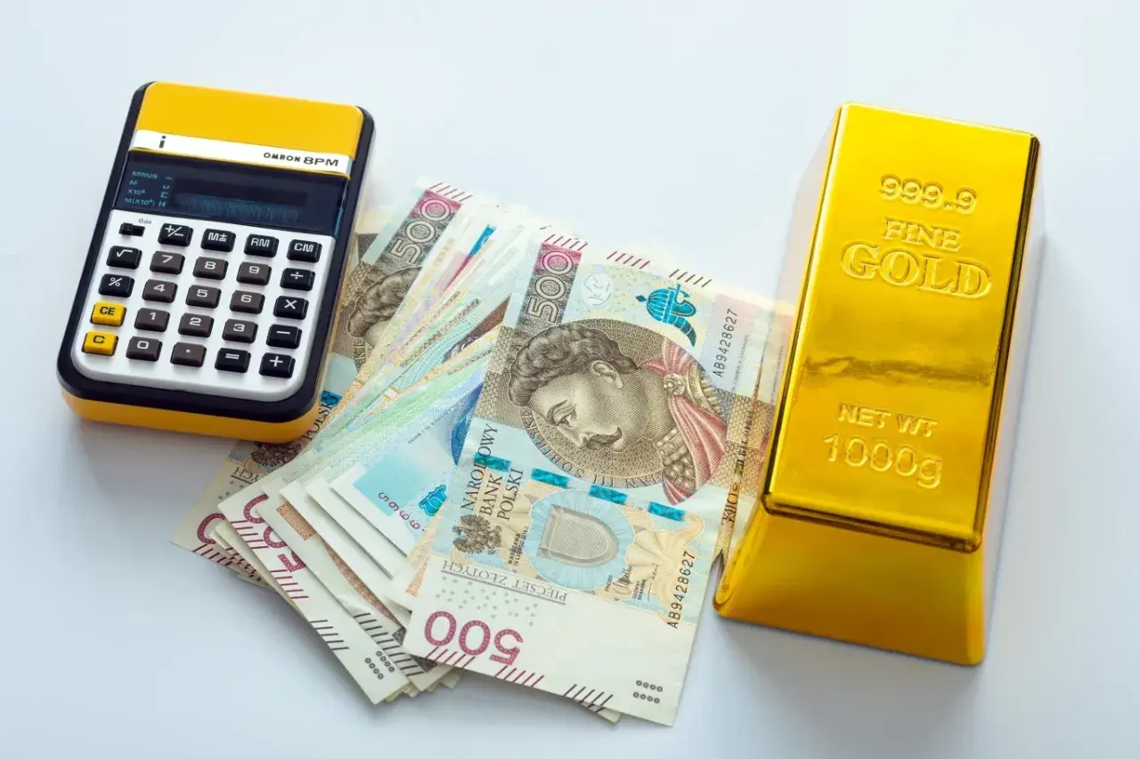 Kalkulator, polskie banknoty 500 zł i sztabka złota 1000g. Zastanawiasz się, ile kosztuje 1 uncja złota?