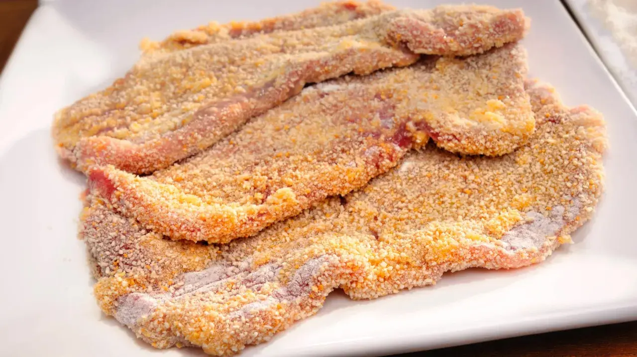 Mehrere panierte Schnitzel liegen auf einem weißen Teller, bereit für ein köstliches Schnitzel Rezept.