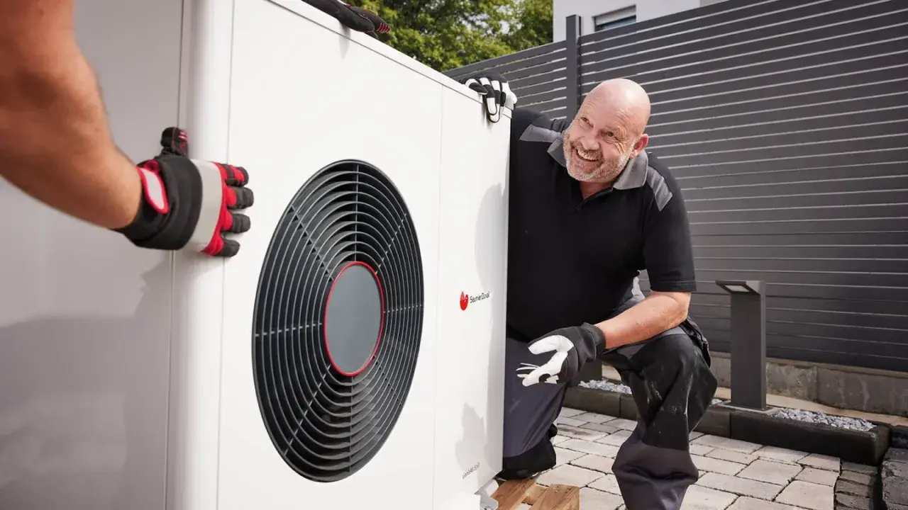 Un technicien souriant aide à installer une pompe à chaleur air air, un système efficace pour le confort de votre maison.