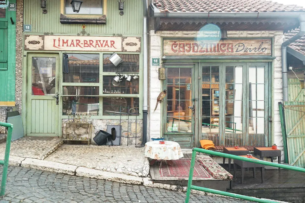 Faszinierende Szene in der Sarajevo Altstadt: Ein Vogel sitzt auf einem Geschäftsschild, davor ein Tisch mit Blumen.