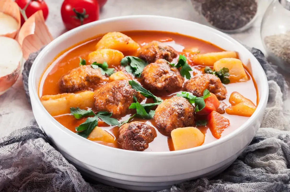 Zupa klopsowa babci: aromatyczne klopsiki w pomidorowym sosie z ziemniakami i natką pietruszki.