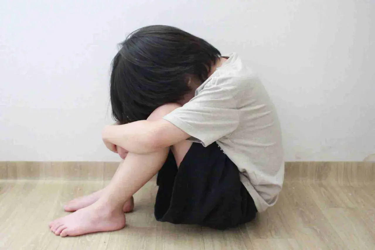Bambino rannicchiato, un'immagine che evoca la necessità di capire come aiutare un figlio depresso.