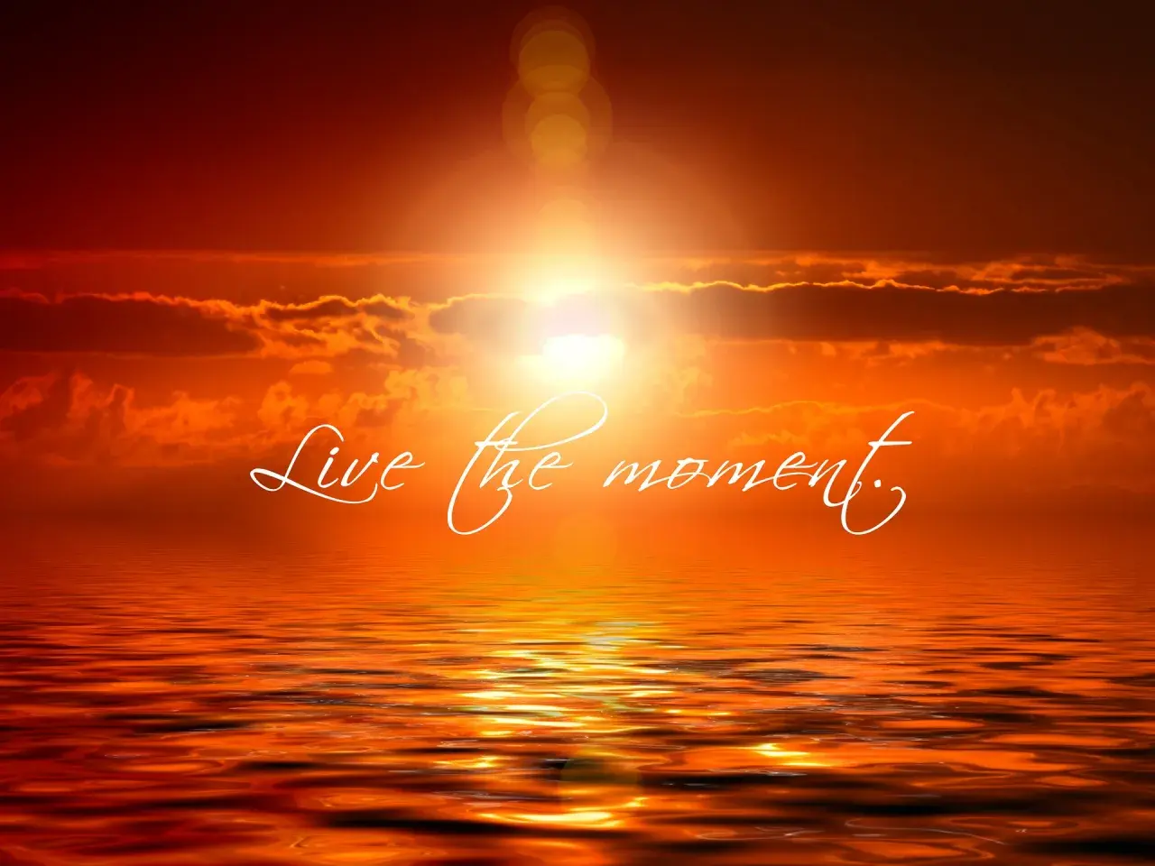 Tramonto infuocato sull'oceano, con la scritta "Live the moment" che invita a vivere il presente.