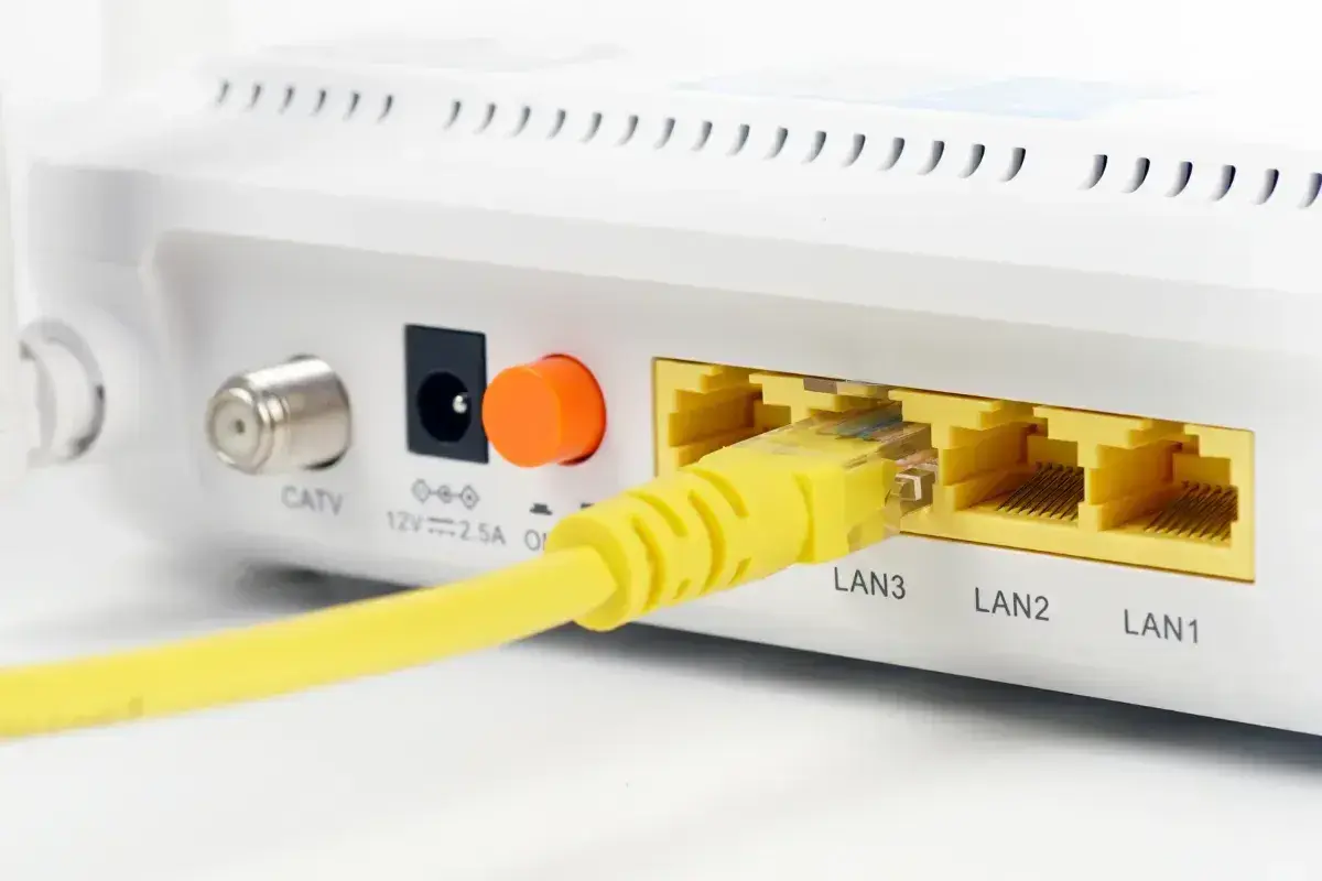 Żółty kabel sieciowy podłączony do portu LAN3 routera. Obok widoczne porty LAN2 i LAN1.