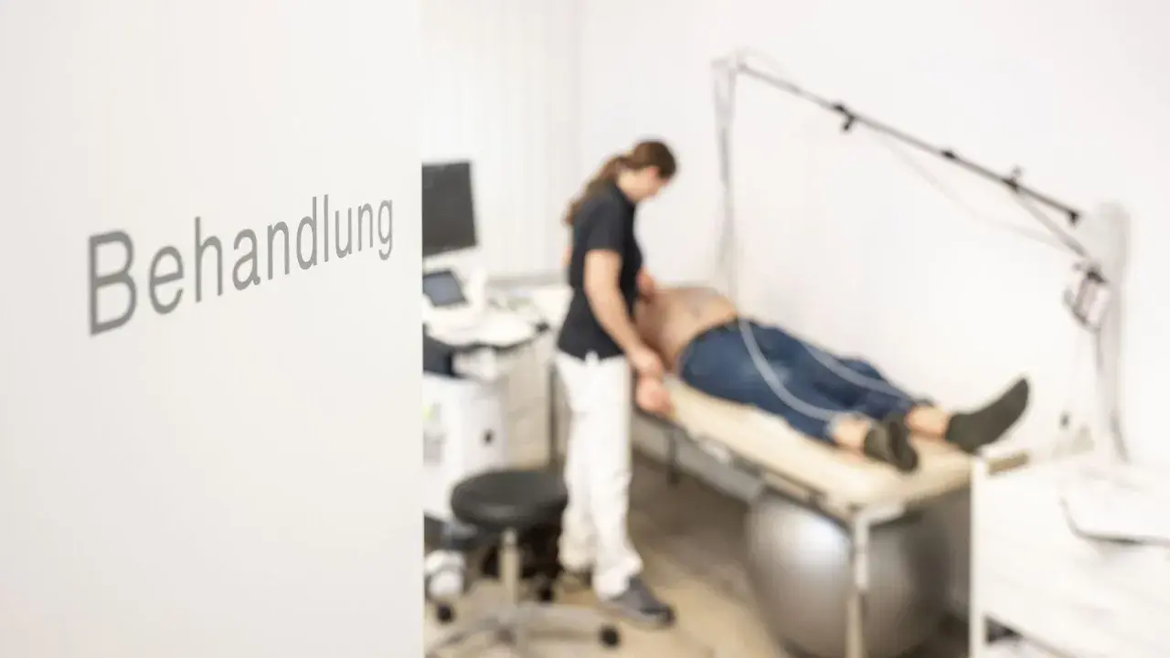 Ärztin untersucht Patienten auf Liege. Ein Ultraschallgerät steht bereit. Was tut dem Herz gut? Diese Behandlung.